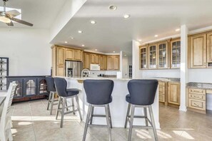 A spacious kitchen with wooden cabinets, a central island with bar stools, and a ceiling fan. - Waterfront Secured Compound in West Ocean City: Your Dream Escape (Ocean City)