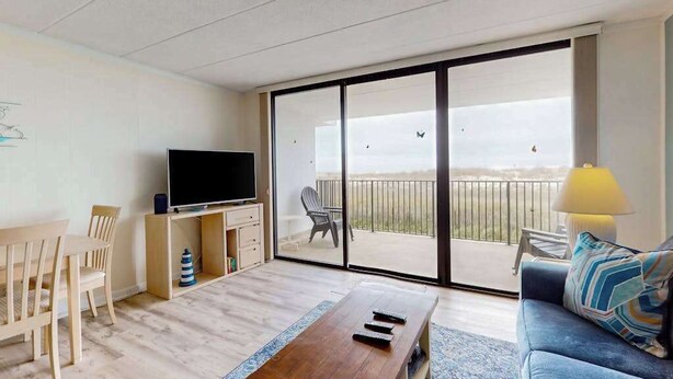Een moderne woonkamer met een flatscreen televisie, een bank, een salontafel en een balkon met uitzicht.