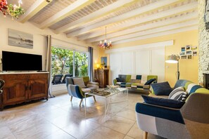 A living room with a TV, sofa, coffee table, and a fireplace. - Maison Maviela, 800 m from the ocean, Soulac (Soulac-sur-Mer)