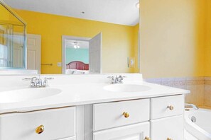 Casa de banho com duas pias, um espelho e uma banheira.