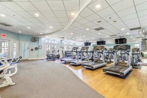 Un gimnasio con cintas de correr, elípticas y equipo de pesas.
