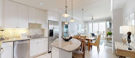 Una cocina moderna con armarios blancos, una isla central e iluminación colgante.