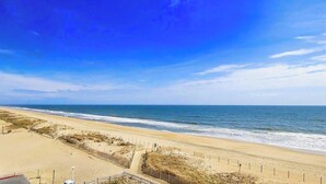 A beach with a clear sky, sandy shore, and a fence along the water's edge. - Gateway Grand 507 (Ocean City)