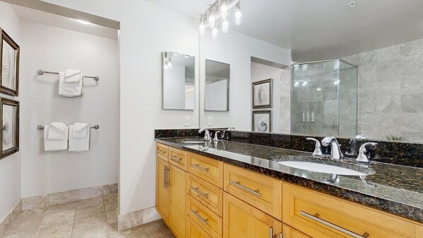 A modern bathroom with a large mirror, two sinks, and wooden cabinets. - Gateway Grand 507 (Ocean City)