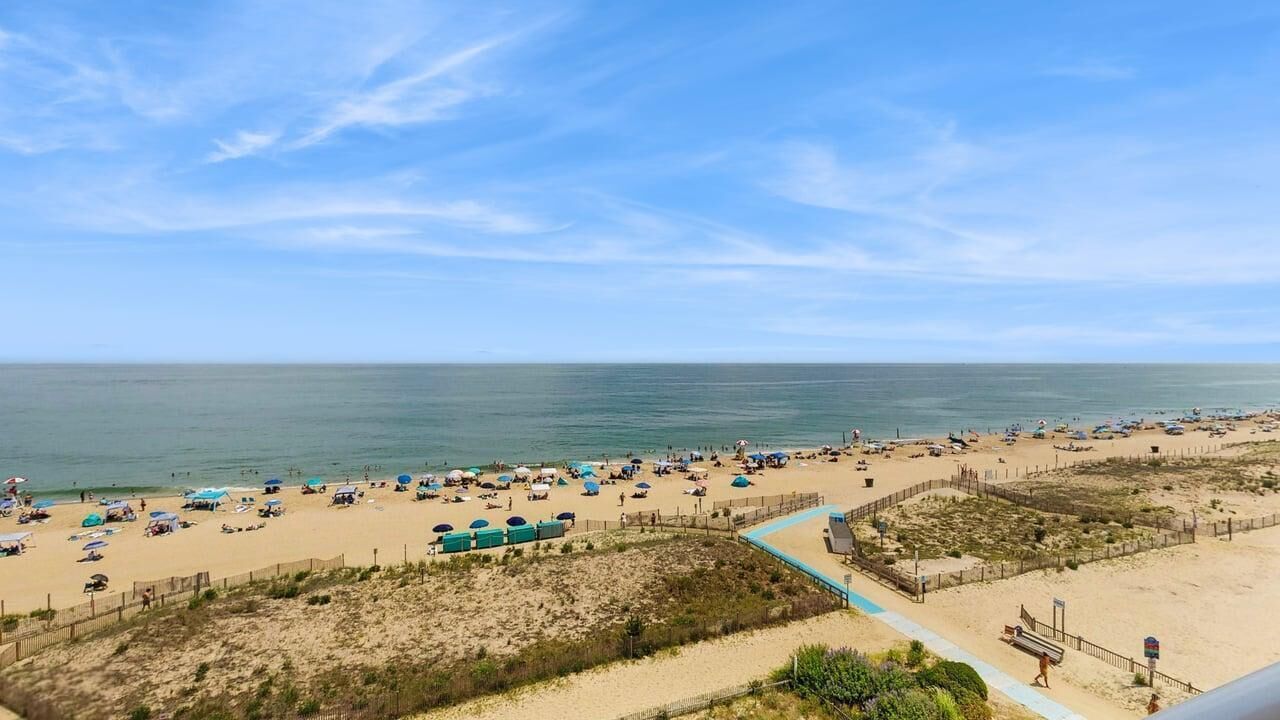 A beach with umbrellas, a fence, and a boardwalk.