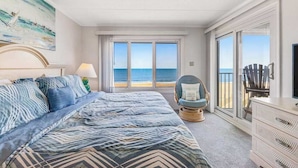 Een slaapkamer met een groot bed, een stoel, een dressoir en een schilderij van een zeilboot.