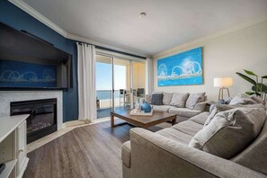 Ein modernes Wohnzimmer mit Kamin, einer Sofagarnitur, einem Couchtisch und einem großen Gemälde einer Brücke.