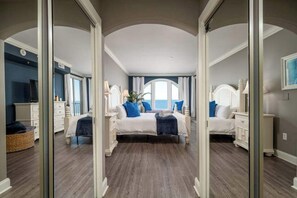 Ein Schlafzimmer mit einem großen Spiegel, zwei Betten, einer Kommode und Meerblick.