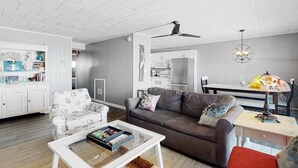 Ein modernes Wohnzimmer mit einer Couch, einem Couchtisch und einem Essbereich mit Tisch und Stühlen.