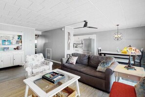A modern living room with a sofa, coffee table, and a dining area with a table and chairs. - Oceanfront Calypso Condo w/ Ocean View Balcony, WiFi, Laundry & Shared Pool (Ocean City)