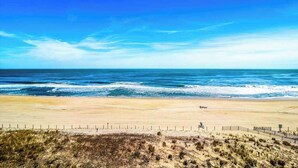 Ein Strand mit einer Umzäunung, dem Ozean und blauem Himmel.