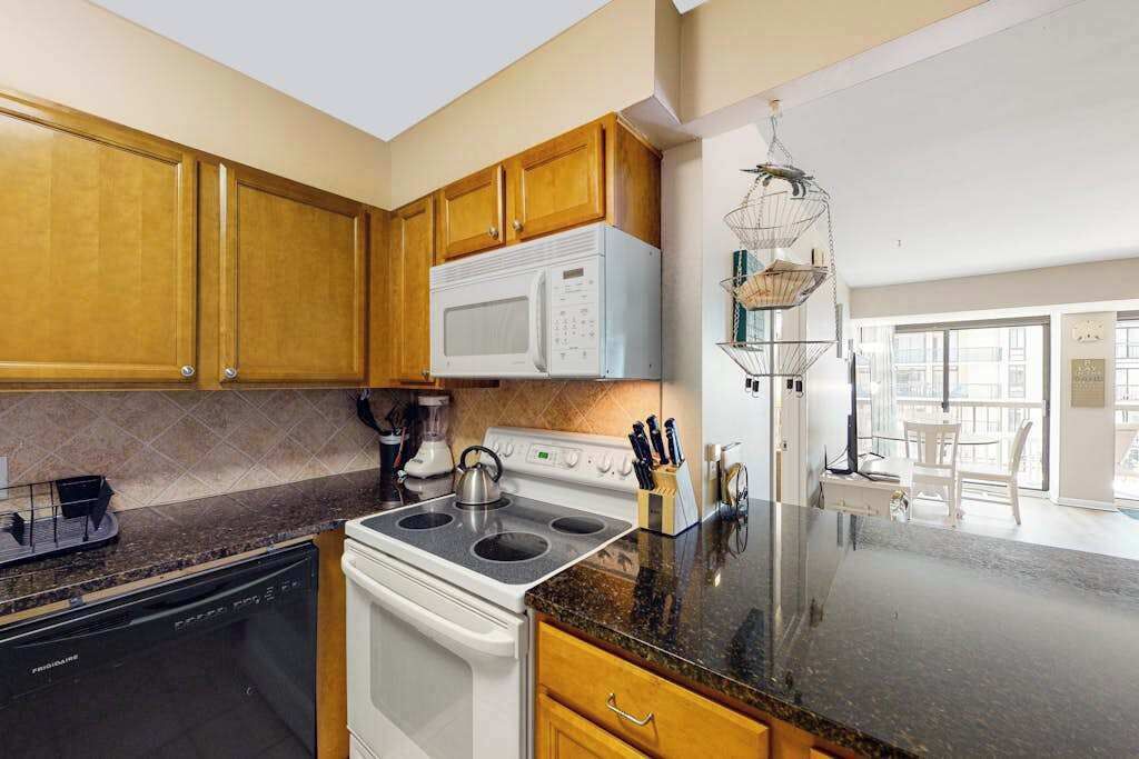 A kitchen with wooden cabinets, a white microwave, a stove, and a dishwasher.