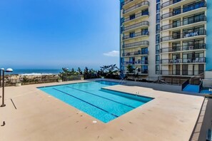 Ein Swimmingpool mit Blick auf den Ozean und einem Hochhaus im Hintergrund.