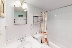 A bathroom with a sink, toilet, shower curtain, and a mirror with lights. - Gorgeous oceanfront condo with pool, central AC, WiFi, balcony water views (Ocean City)