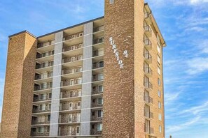 A multi-story building with a brick facade, balconies, and the name 'SURFSIDE' on the side. - Gorgeous oceanfront condo with pool, central AC, WiFi, balcony water views (Ocean City)