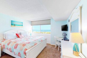 A bedroom with a bed, a desk, a chair, a TV, and a window with a view. - Gorgeous oceanfront condo with pool, central AC, WiFi, balcony water views (Ocean City)