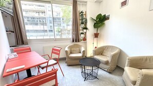 A furnished living room with a dining table, chairs, a sofa, a small round table, and a potted plant. - Maison Du Grand Sud 2 - Promenade Des Anglais (Nice)
