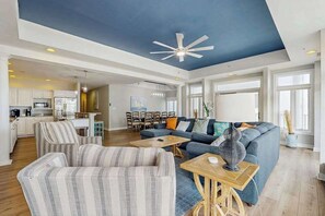 A spacious living area with a large sofa, a dining table, and a kitchen in the background. - Bright, Modern Beach Home Steps From Water w/Ocean Views, Central AC, WiFi, W/D (Ocean City)
