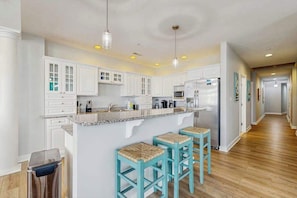 A kitchen with white cabinets, a granite countertop, a refrigerator, and two bar stools. - Bright, Modern Beach Home Steps From Water w/Ocean Views, Central AC, WiFi, W/D (Ocean City)