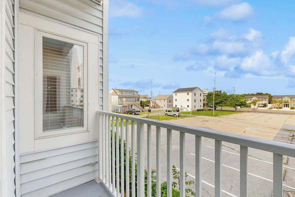 Ein Wohngebäude mit Balkon, Parkplatz und umliegenden Häusern.