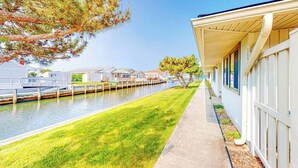 A waterfront hotel with a grassy walkway, a dock, and a row of buildings along the water. - Beach Club 127 A (Ocean City)