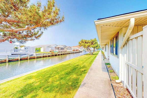 A waterfront hotel with a grassy walkway, a dock, and a row of buildings along the water. - Beach Club 127 A (Ocean City)