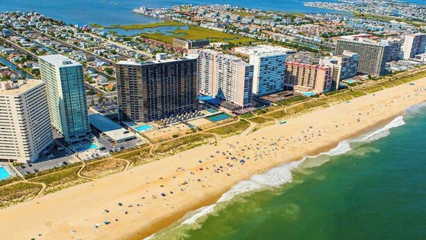 A coastal cityscape with high-rise buildings, a sandy beach, and a marina. - Beach Club 127 A (Ocean City)