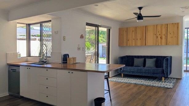 A modern kitchen with a wooden countertop, white cabinets, and a built-in dishwasher. - Welcoming 3-Bed House with Large Backyard (Mandurah)