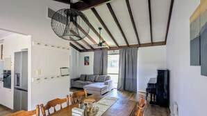 A spacious living area with a dining table, sofa, and a unique ceiling light fixture. - Welcoming 3-Bed House with Large Backyard (Mandurah)