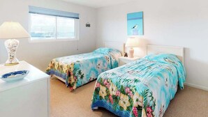 Une chambre avec deux lits, une fenêtre avec des stores, un tableau accroché au mur et une table de chevet avec une lampe.