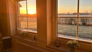 Una habitación con un ventanal grande que da a un paisaje nevado al atardecer.