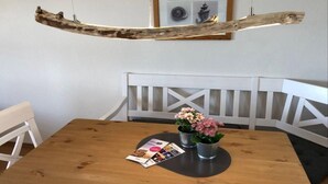 Una mesa de madera para comer con dos macetas de metal, un folleto y una viga de madera en el techo.
