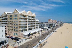 Ein mehrstöckiges Hotel mit Balkonen, einer Promenade und einem Strand im Hintergrund.
