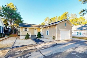 Une maison de plain-pied avec un garage à l’avant, un petit porche et une pelouse bien entretenue.