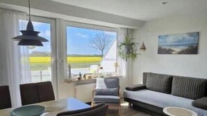 Un salon moderne avec un coin repas, de grandes fenêtres et une vue sur la campagne.