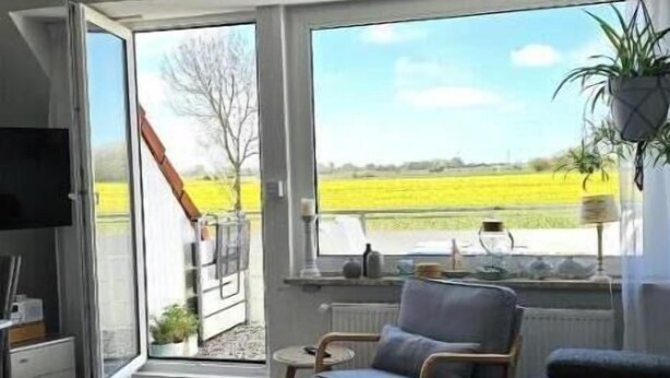 Un salon moderne avec un canapé, un fauteuil, une petite table et un téléviseur.