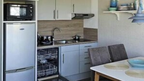 Une cuisine compacte équipée d’un four à micro-ondes, d’un réfrigérateur, d’un lave-vaisselle et d’une table à manger avec des chaises.
