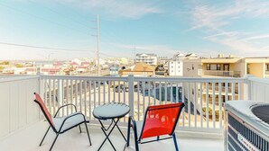 A balcony with two chairs and a table, overlooking a cityscape with buildings and a street. - Siesta Villa 304N (Ocean City)
