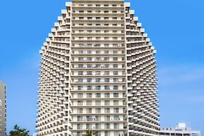A high-rise building with a unique angular design, featuring multiple balconies and a uniform facade. - Incredibly Convenient Beach Condo w/Balcony, W/D, A/C, Shared Pools, Gym, Tennis (Ocean City)