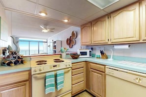 A kitchen with wooden cabinets, a stove, a microwave, and a dishwasher. - Boca Grande 504 (Ocean City)