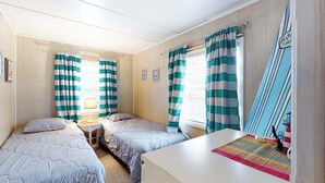 A room with two beds, a small table with a lamp, and a surfboard decoration. - First-Floor, Ocean Block Condo with Patio, AC, WiFi & Laundry - Steps to Beach (Ocean City)
