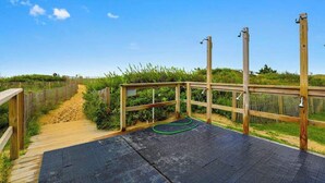 A wooden deck with a black rubber mat, surrounded by a wooden fence and greenery. - Astounding beach condo with balcony, pools, gym, game room & tennis (Ocean City)