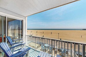 A balcony with blue chairs, a view of the beach, and a clear sky. - Belmont Towers 305 (Ocean City)