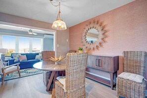 Ein modernes Wohnzimmer mit Korbmöbeln, einem runden Tisch und einem großen Spiegel an der Wand.