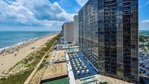 Ein Hochhaus-Hotel mit Blick auf den Strand, mehreren Balkonen und einem Poolbereich.