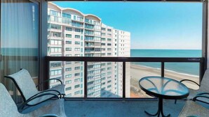 Ein Balkon mit Blick auf einen Strand und ein Hochhaus.