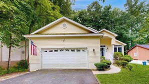 A single-story house with a garage, surrounded by greenery and trees. - Coral Shells (Ocean Pines)
