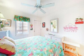 A bedroom with a bed, a ceiling fan, a window with curtains, a dresser, a mirror, and wall decorations. - Ocean Block Condo w/ Balcony, Ocean View, Central AC & Washer/Dryer (Ocean City)