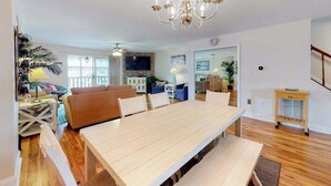 Ein geräumiges Wohnzimmer mit einem großen Esstisch aus Holz, einer Couch und einer Kandelaber.