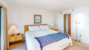 Una camera da letto con un letto, comodini, una lampada, un quadro appeso e una lampada da terra.